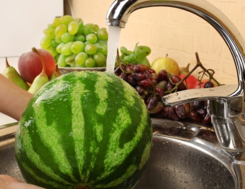 Washing watermelon under a sink